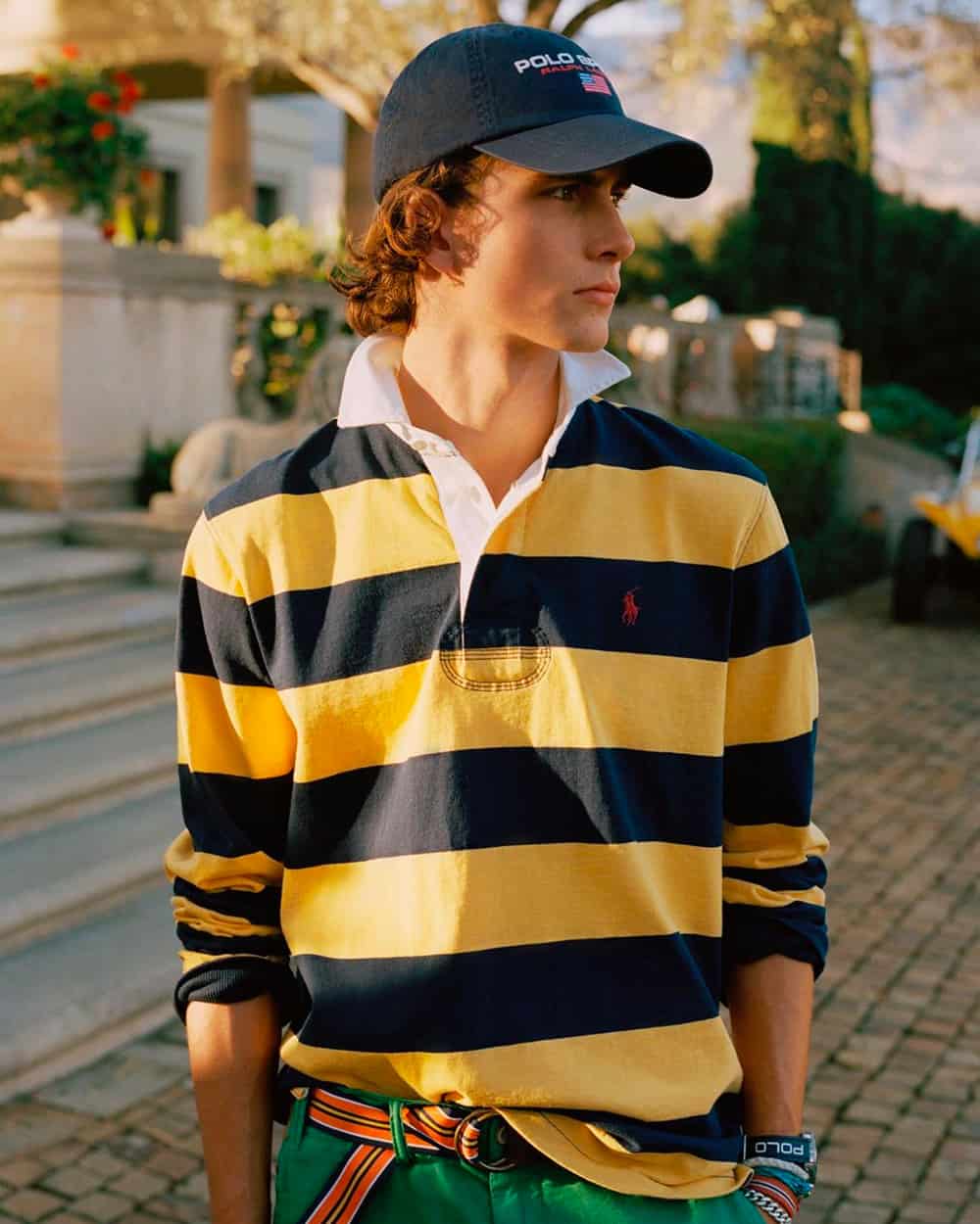 Man wearing Polo Ralph Lauren navy and yellow stripe rugby shirt with green pants and Polo navy baseball cap