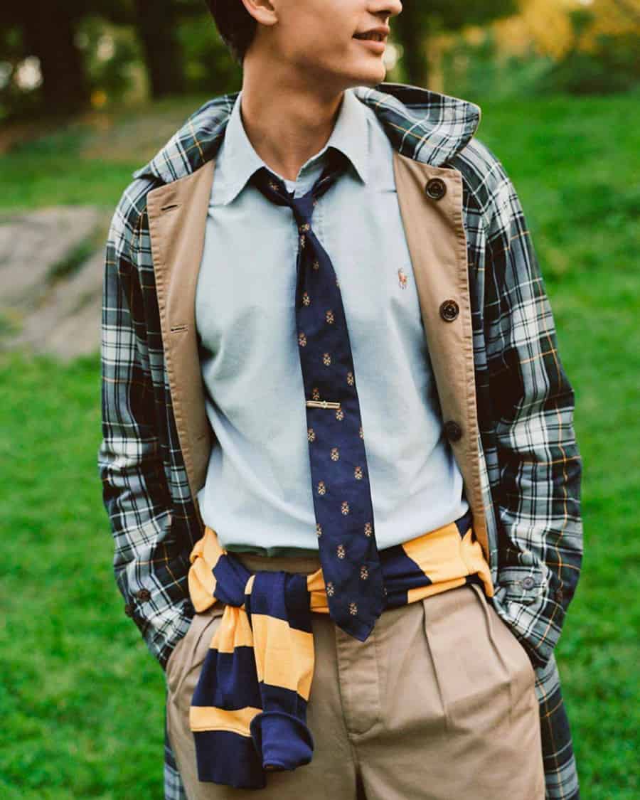 Man wearing preppy light blue shirt, khaki pleated pants and checked jacket