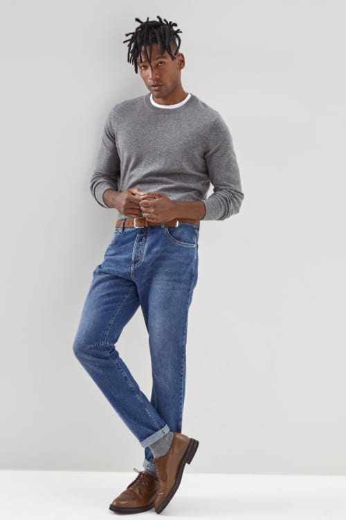 Men's mid wash jeans, white T-shirt, grey sweater and brown leather Derby shoes outfit
