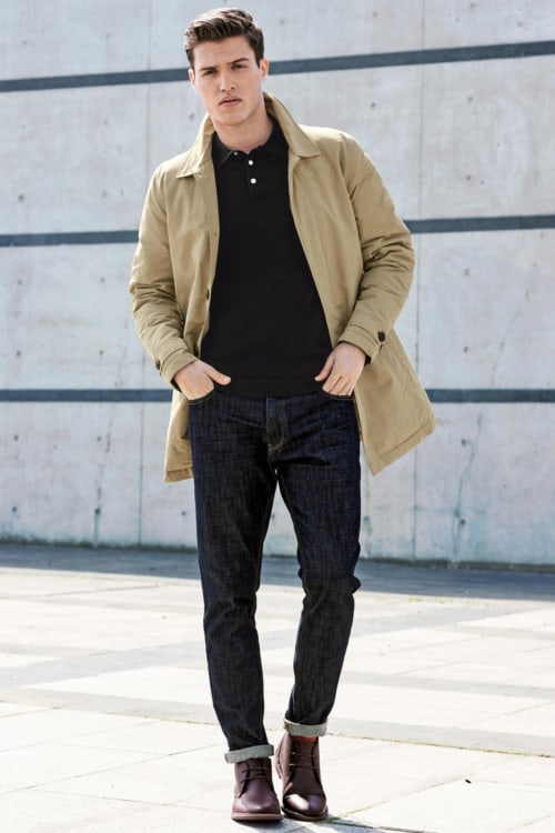 Men's raw denim jeans, leather chukka/desert boots, black polo shirt and beige mac outfit