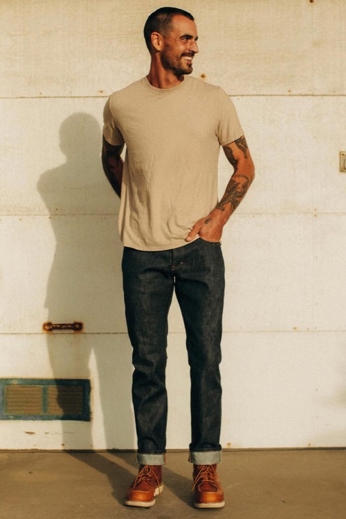 Men's raw denim jeans, tan moc toe work boots and beige T-shirt outfit