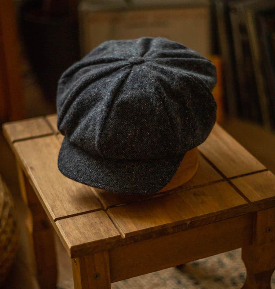 Wool baker boy hat on stand on wooden side table