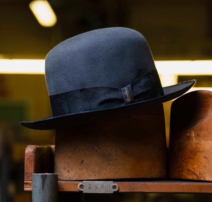 Men's navy bowler hat on wooden stand