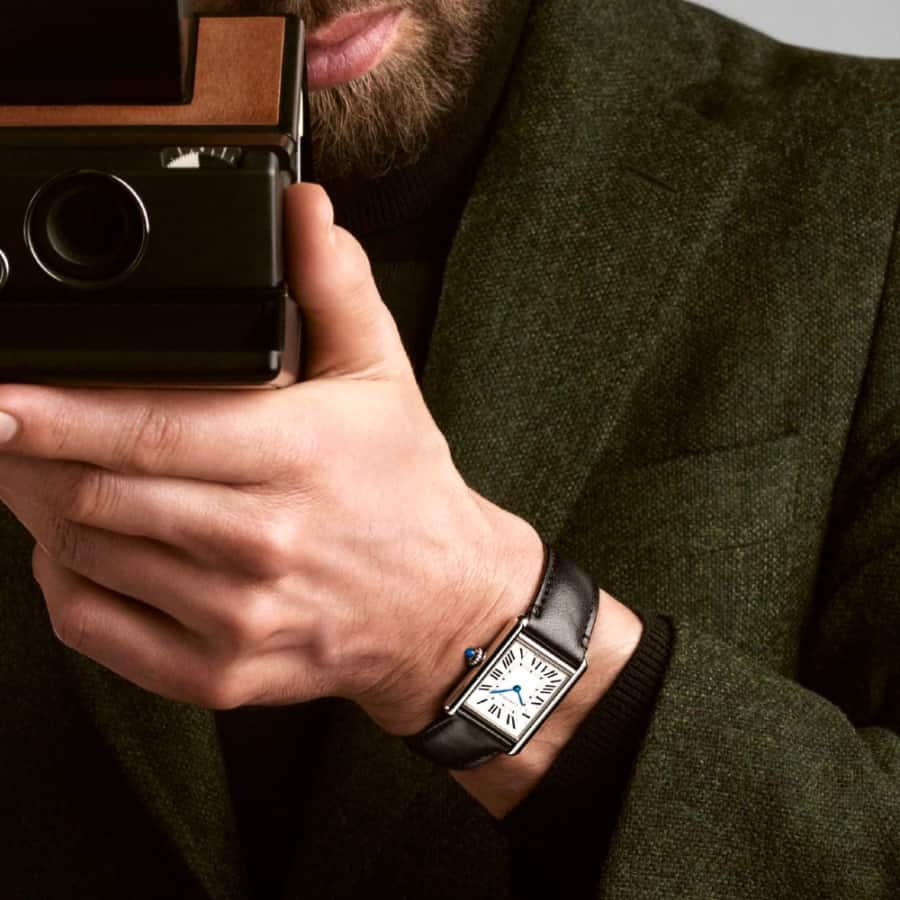 Man with camera taking a picture wearing a classic Cartier Tank Must