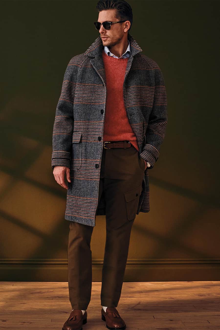 Men's brown cargo pants, blue oxford shirt, red sweater, checked overcoat and brown leather loafers outfit