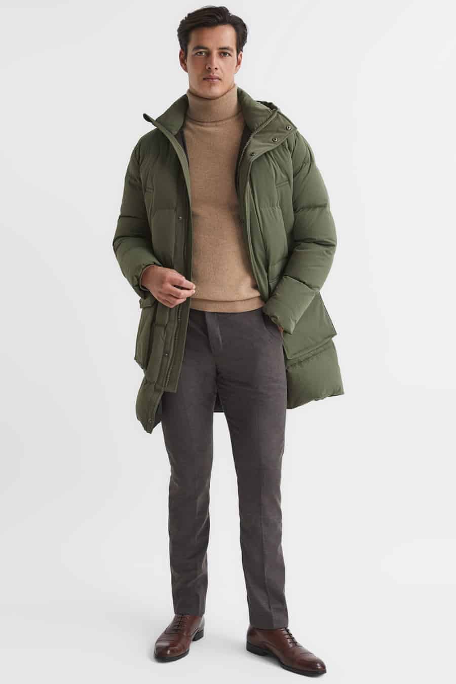 Men's grey wool trousers, camel turtleneck, green puffer jacket and brown oxford shoes outfit