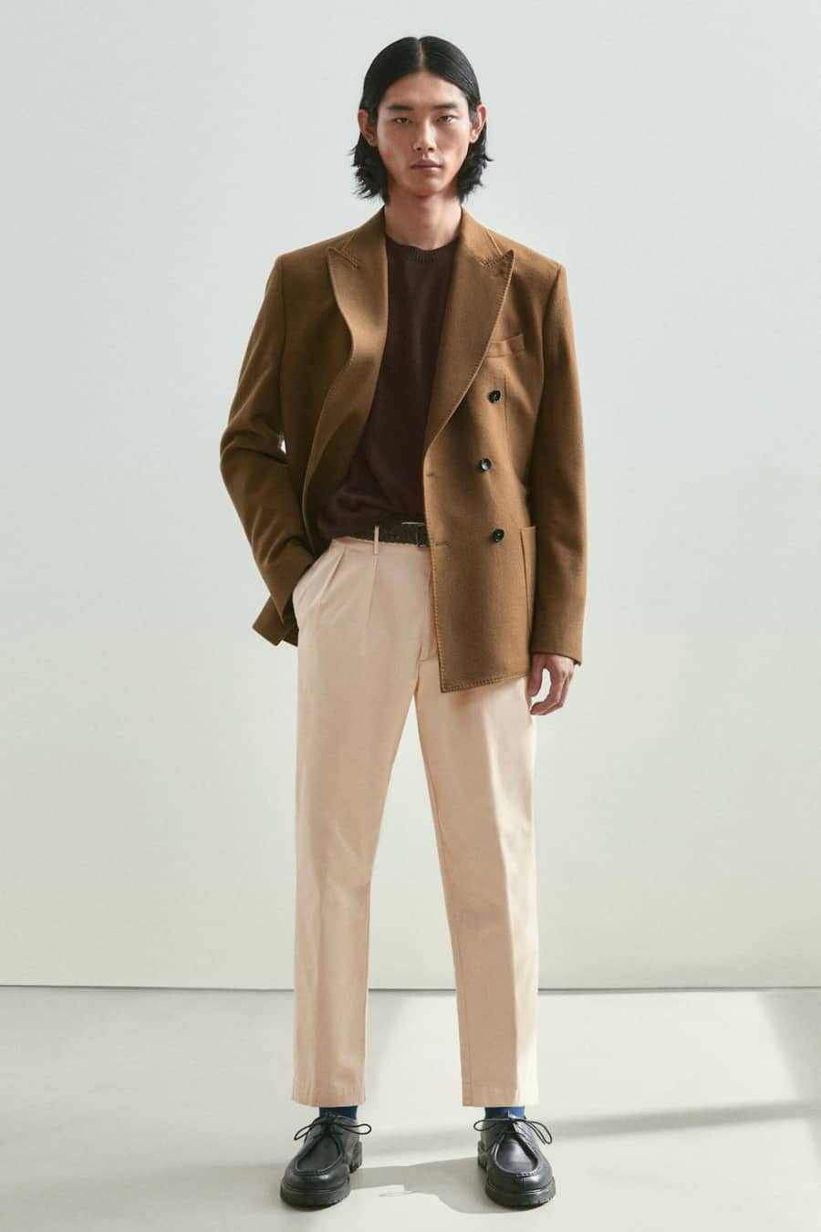 Men's beige pleated trousers. brown T-shirt,. camel brown double breasted blazer and black shoes outfit