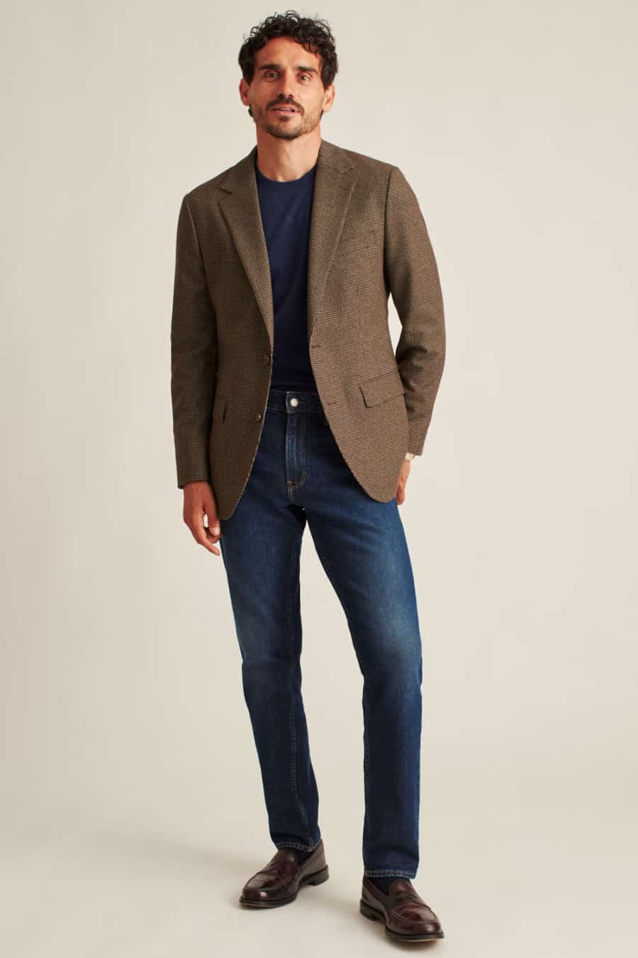 Men's brown wool blazer, tucked in navy T-shirt, mid-wash jeans and loafers outfit