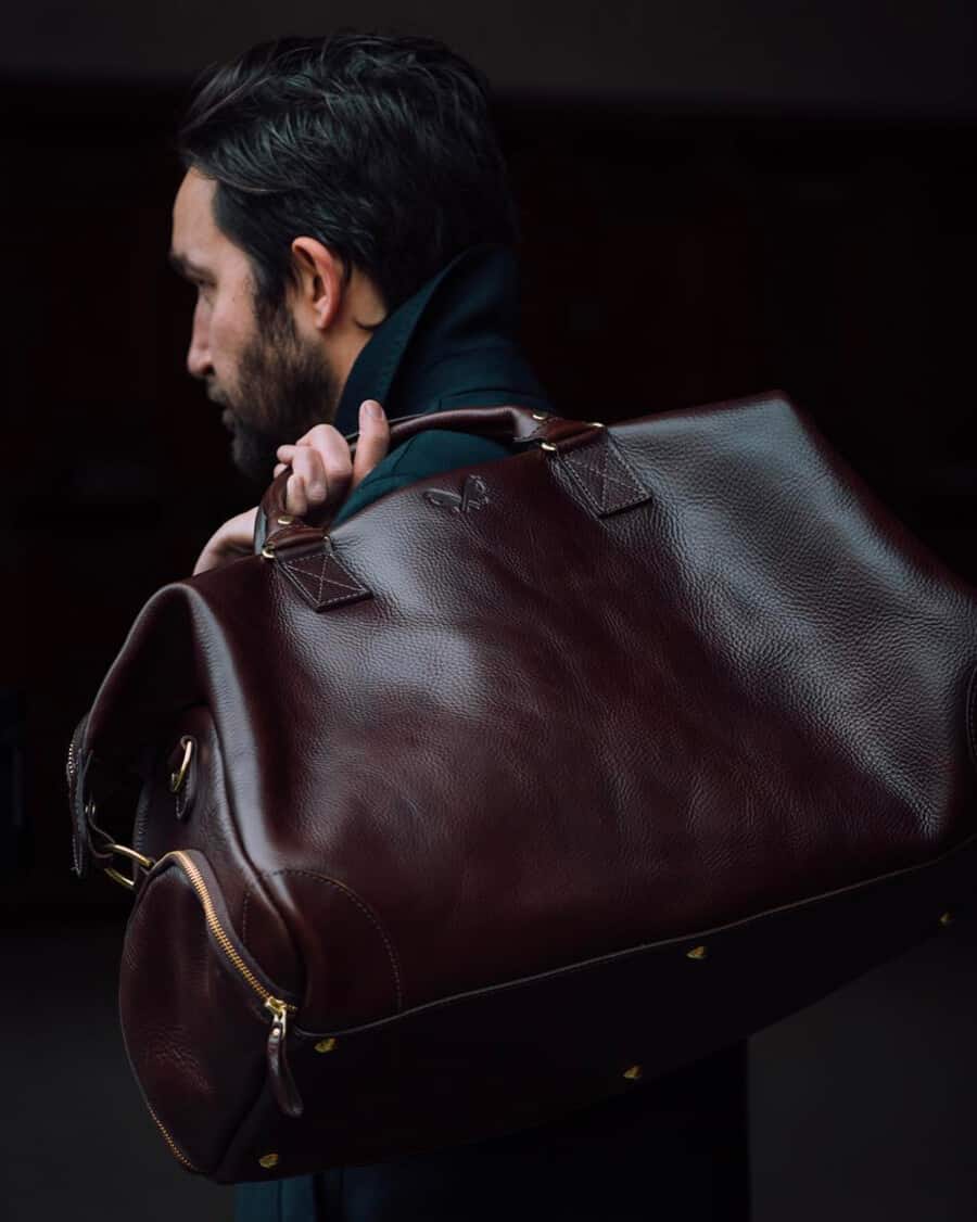 Man carrying a luxury brown leather weekender bag over his shoulder