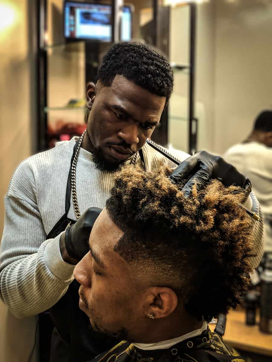 Barber cutting a low skin fade into an afro haircut