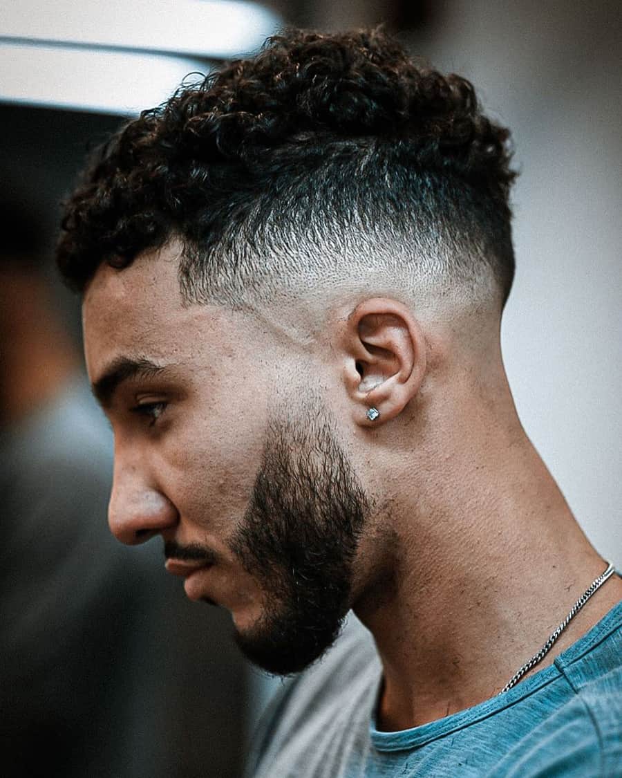 Men's short curly haircut with high skin fade