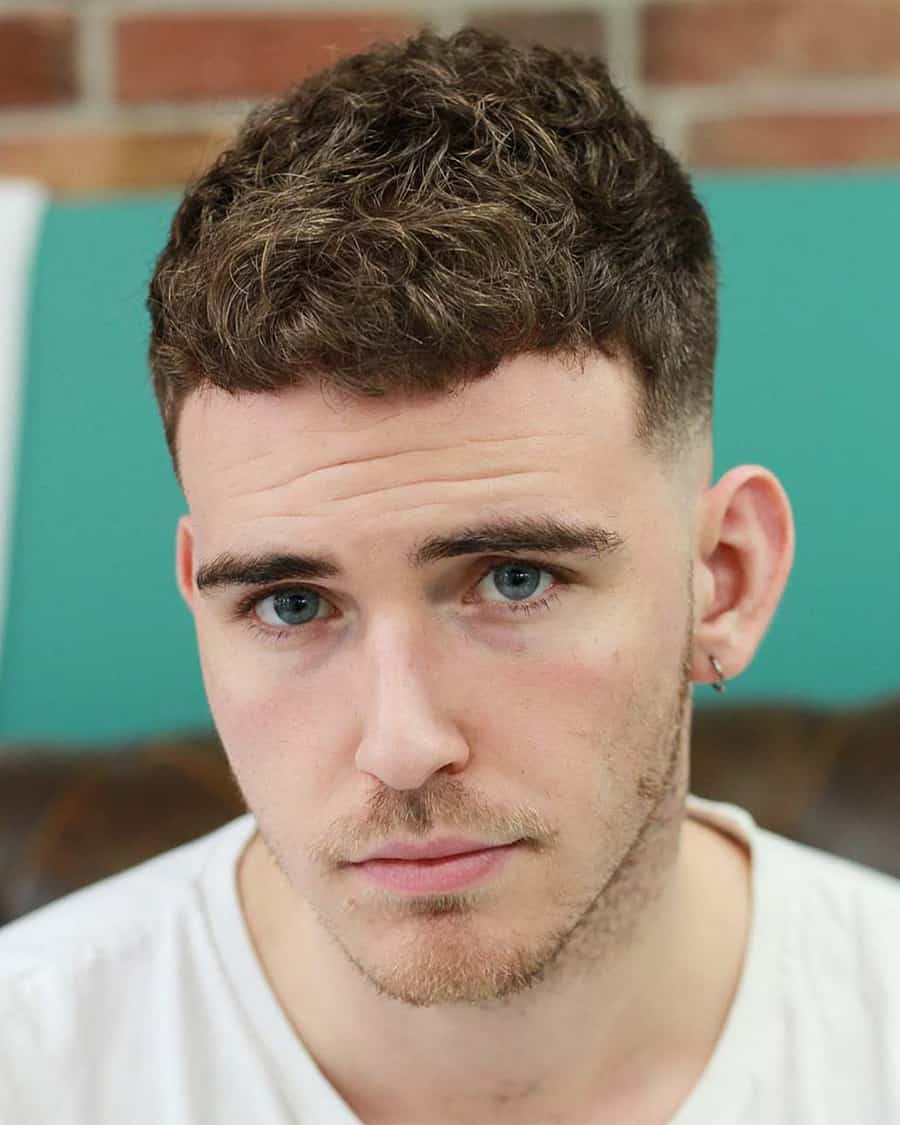 Men's short curly haircut with a low fade