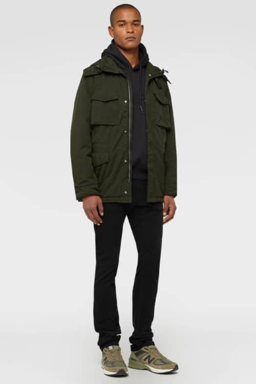 Men's black jeans, black hoodie, green M65 field jacket and New Balance sneakers outfit