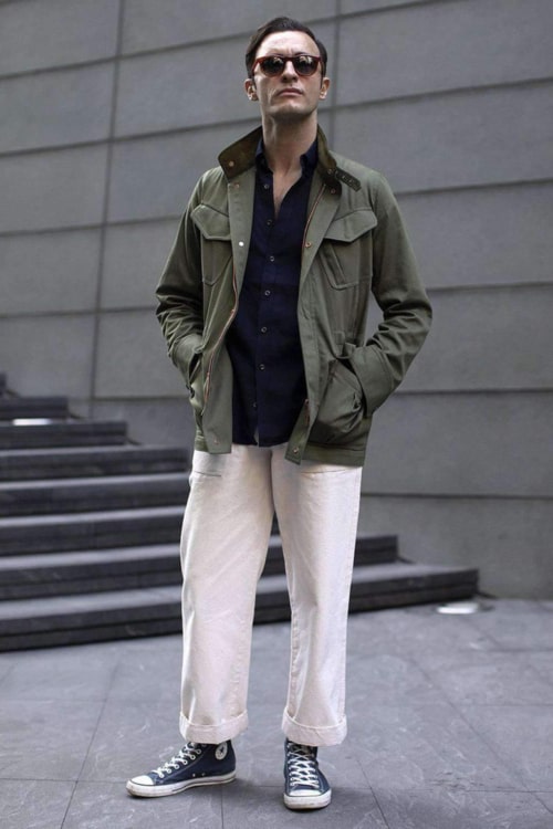 Men's white jeans, blue shirt, green M65 field jacket and Converse high-top sneakers outfit