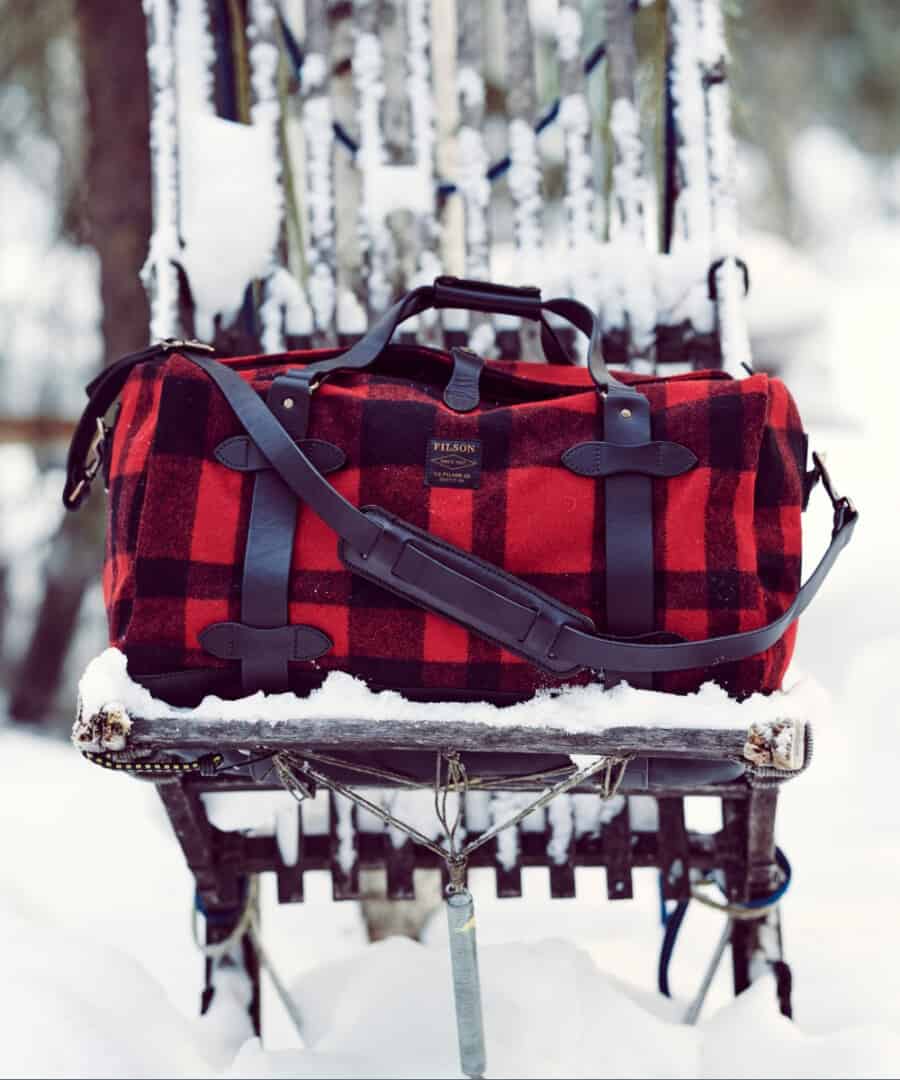 Red and black tartan weekender bag outside on a chair in the snow
