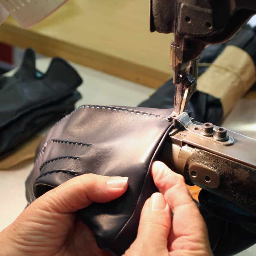 Woman sewing leather gloves together using sewing machine