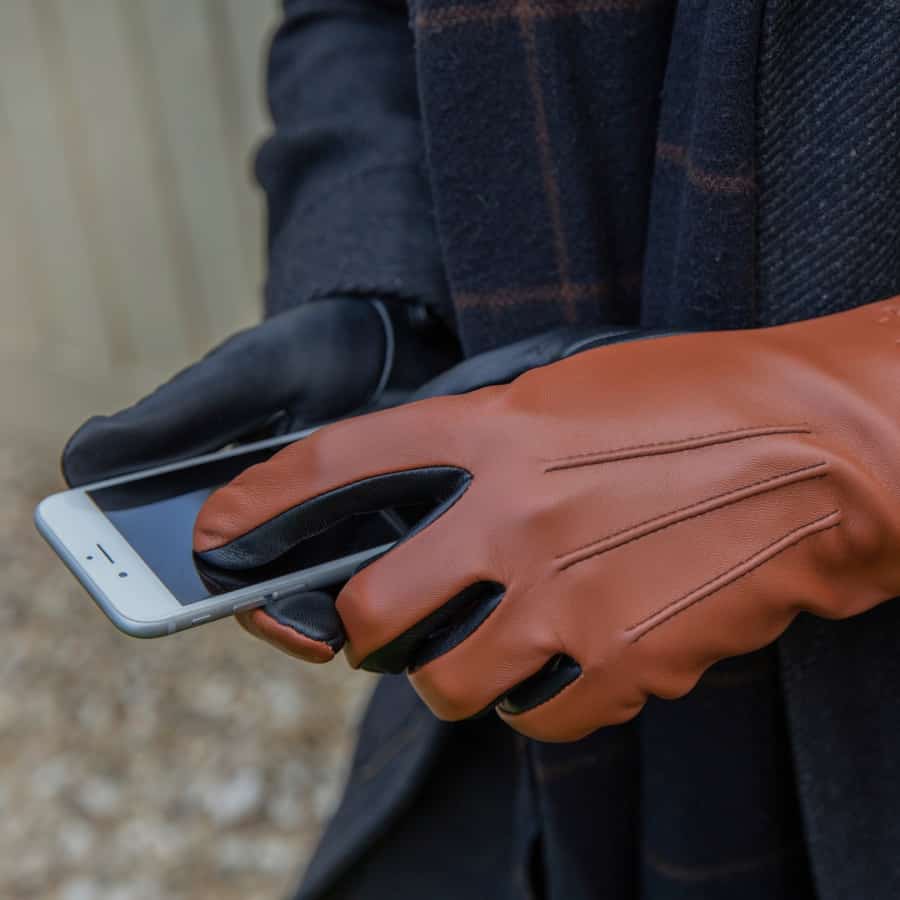 Man wearing brown leather gloves using his smartphone