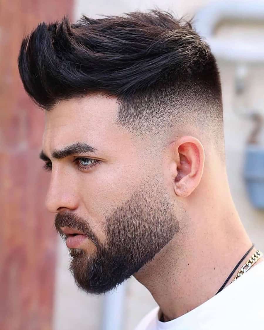 Men's high volume quiff haircut with high skin fade and shaped beard
