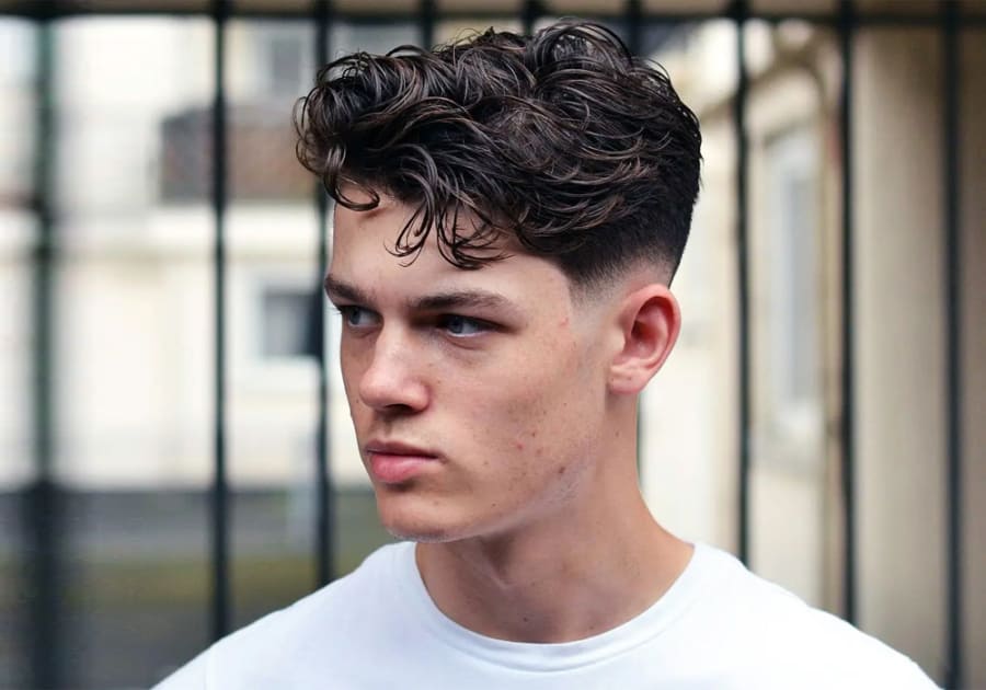Man with curly hair and fringe and a low fade
