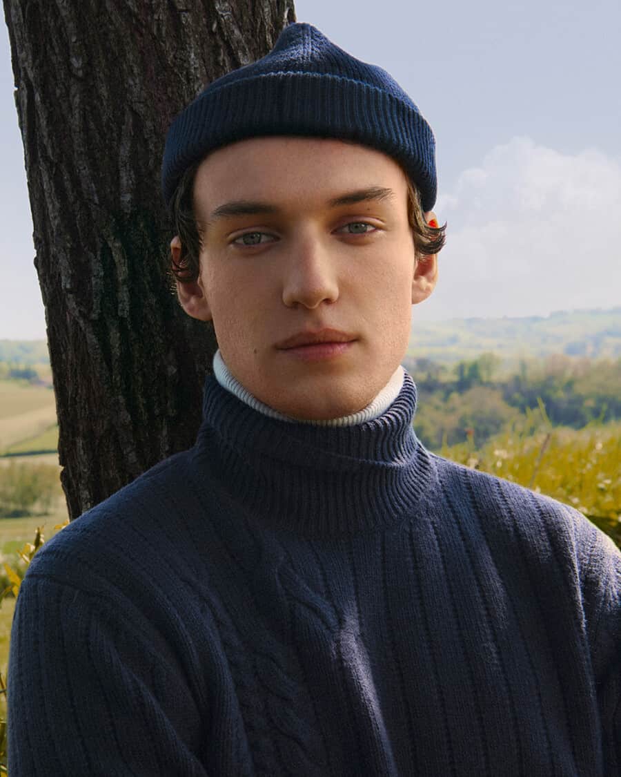 Man wearing a chunky navy roll neck jumper and luxury navy fisherman beanie