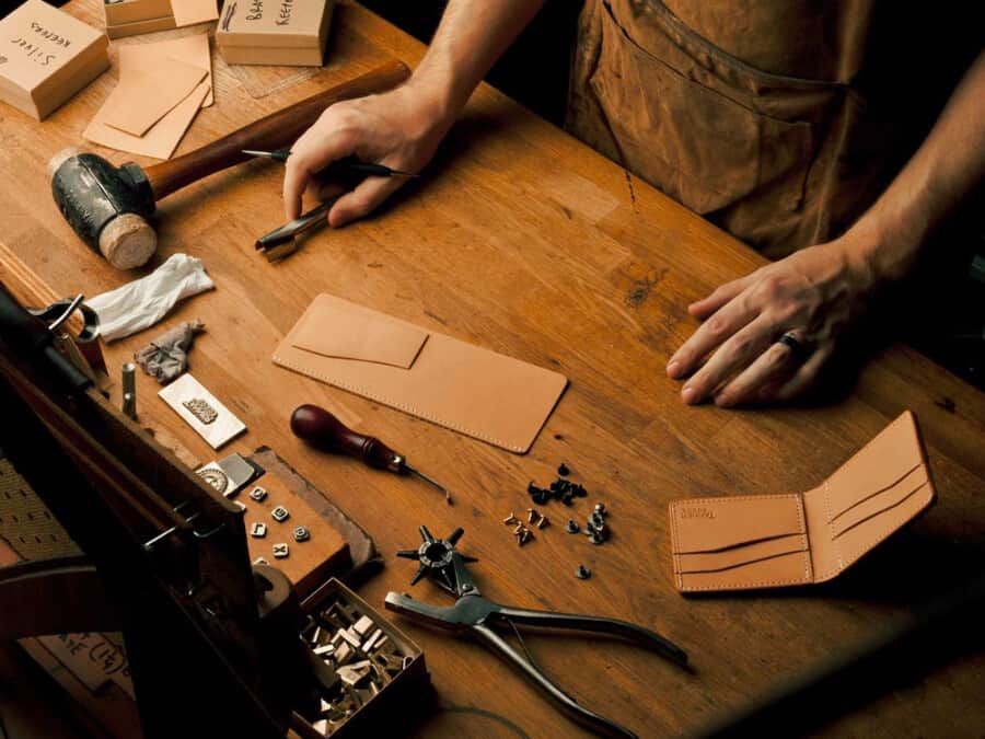 Man handcrafting a luxury leather men's wallet on a workbench in the USA