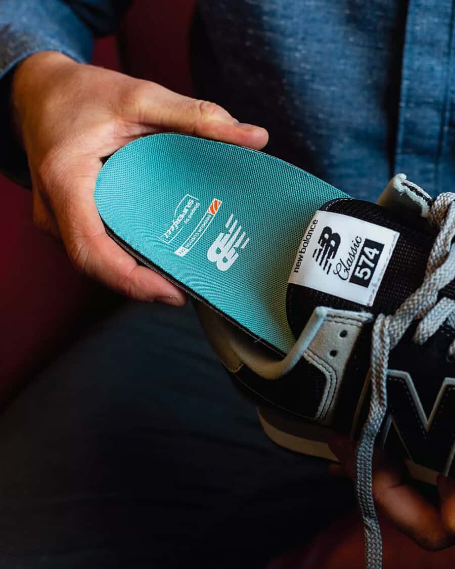 Man slipping a cushioned insole into a sneaker to make it more comfortable