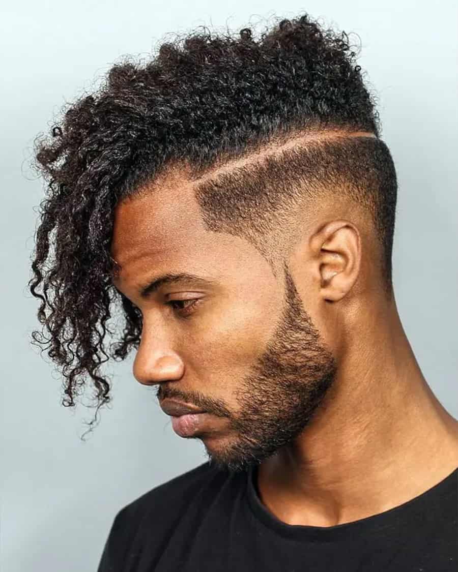 Black man with long curls in a comb over side sweep with a drop fade and hard parting