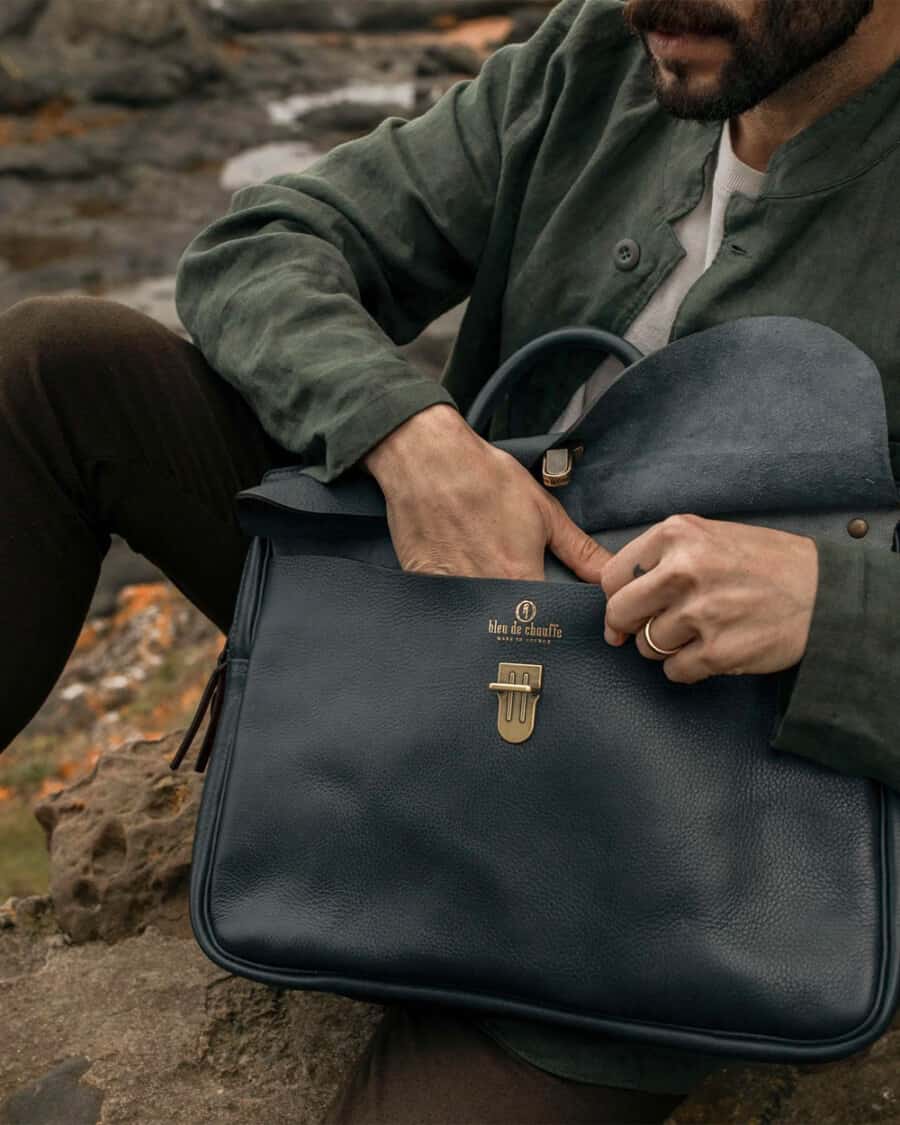 Man putting something in a luxury blue leather messenger bag