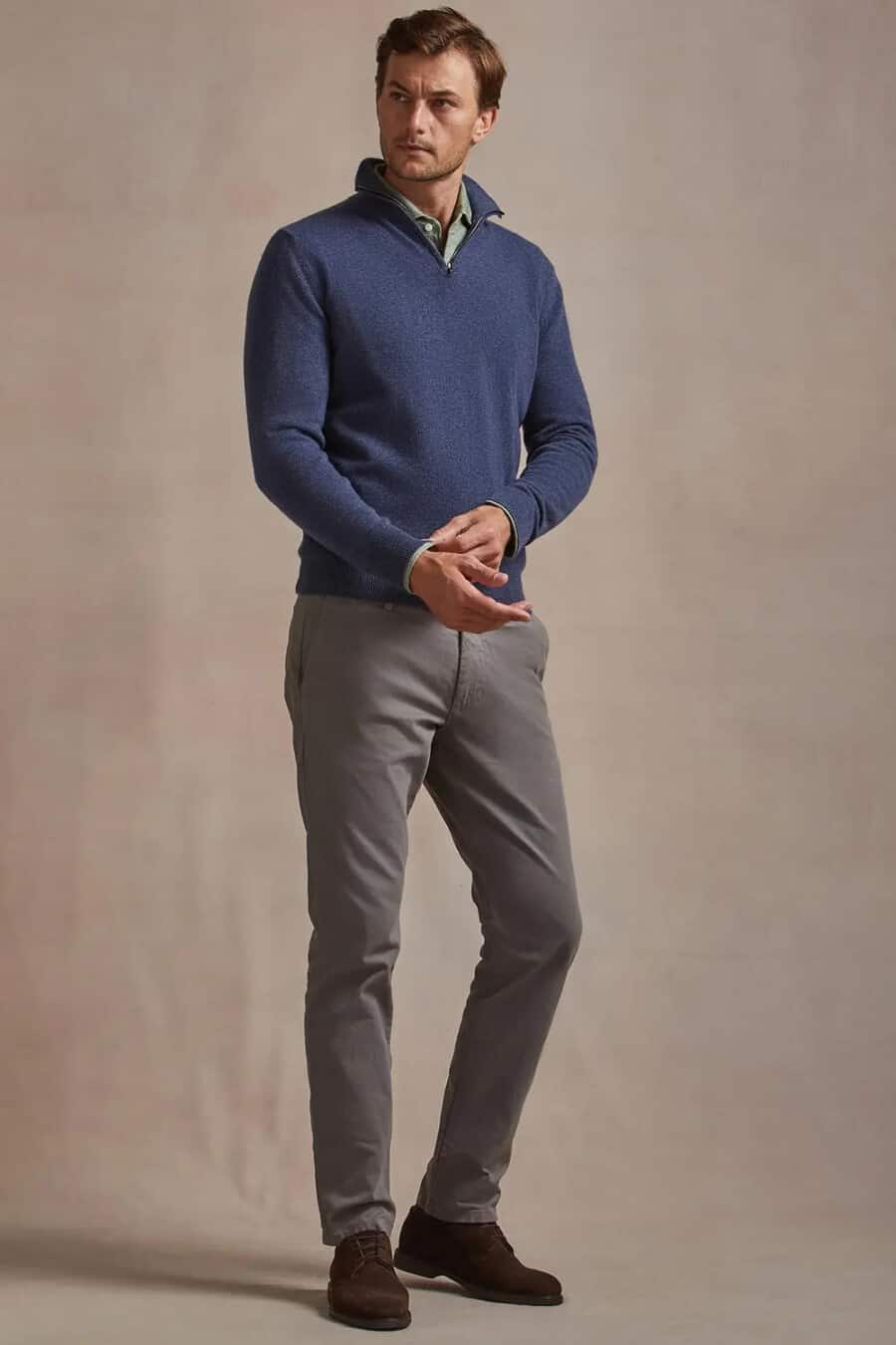Men's grey chinos, green shirt, blue zip neck sweater and brown suede Derby shoes outfit