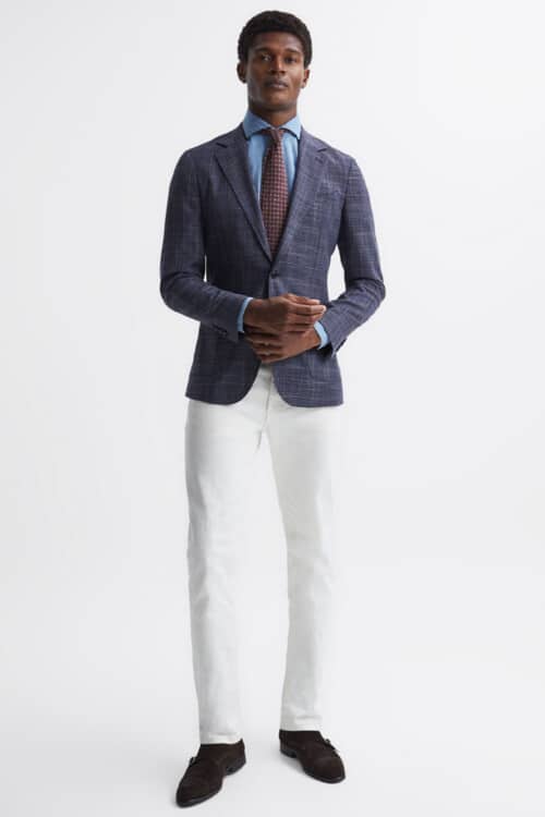 Men's white trousers, light blue shirt, red tie, navy check blazer and brown monk strap shoes outfit