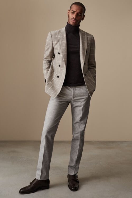 Men's grey wool pants, black turtleneck, checked blazer and brown monk strap shoes outfit