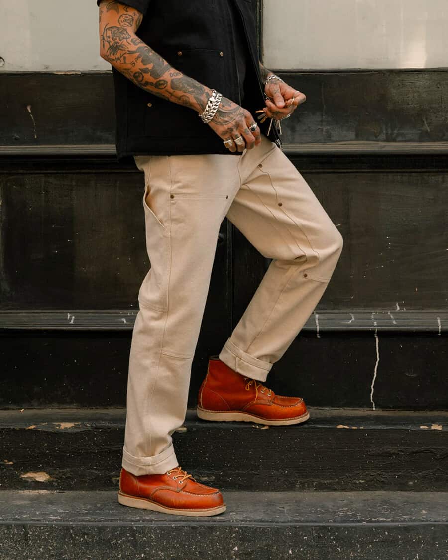 Men's beige carpenter pants with moc-toe boots and black denim shirt
