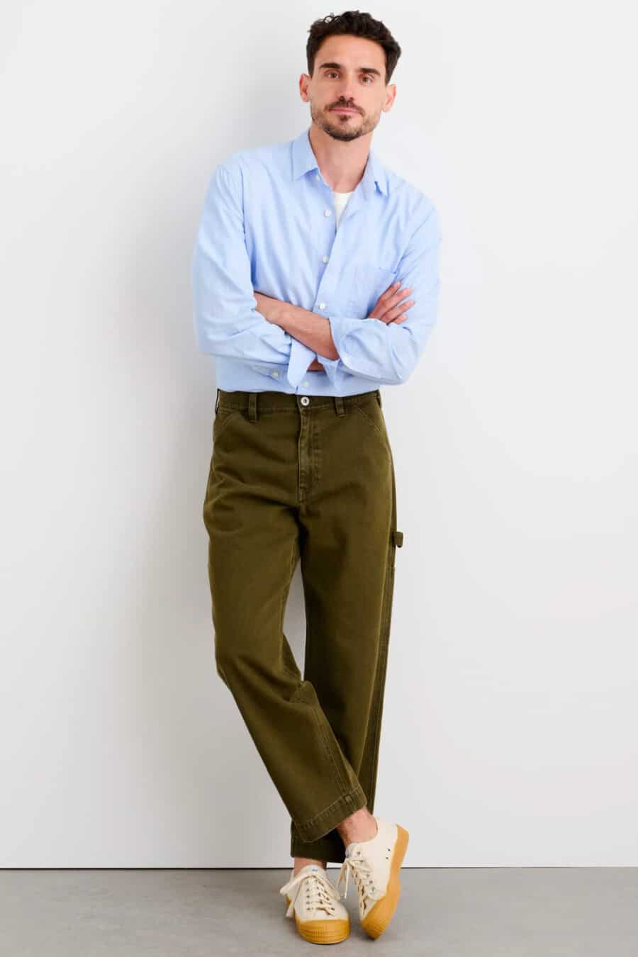 Men's green carpenter pants, light blue Oxford shirt and canvas sneakers outfit