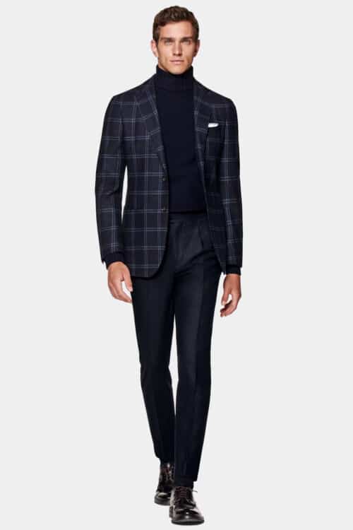 Men's wearing cocktail attire separates. Nabvy trousers, navy check blazer, navy roll neck and brown leather shoes