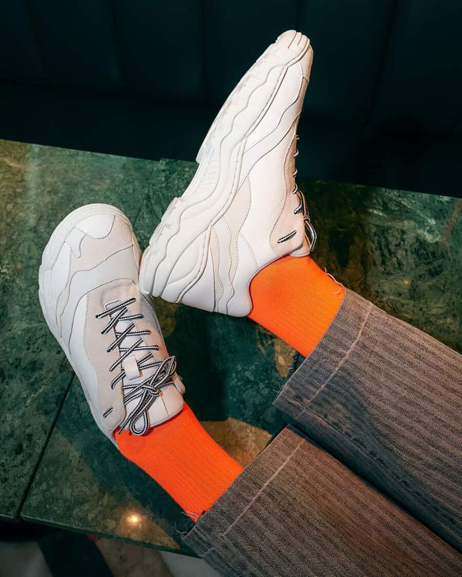 Diverge Landscape sneakers worn on feet with tailored grey pants and bright orange socks