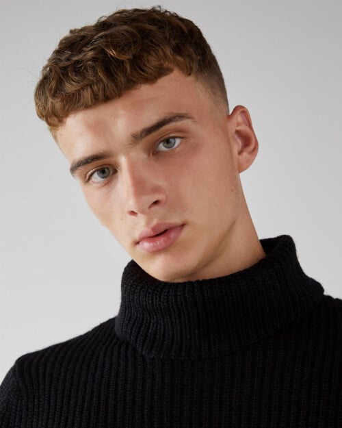 Man with curly hair sporting a short classic French crop haircut with taper fade