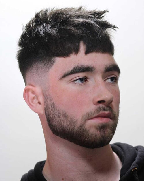 Man with a messy, mid-length French crop haircut and high skin fade