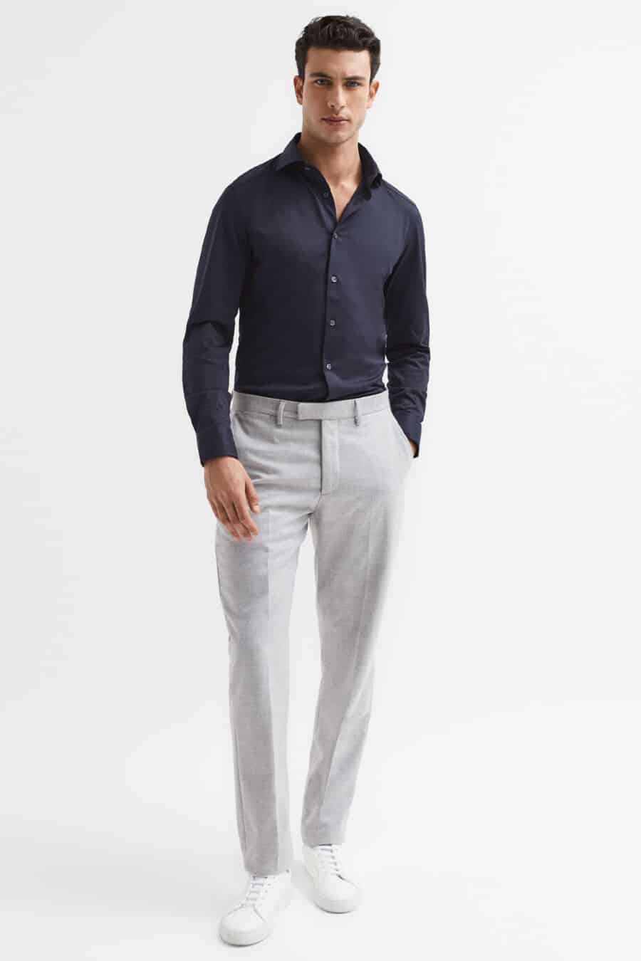 Men's light grey tailored trousers, navy fitted shirt and white sneakers outfit