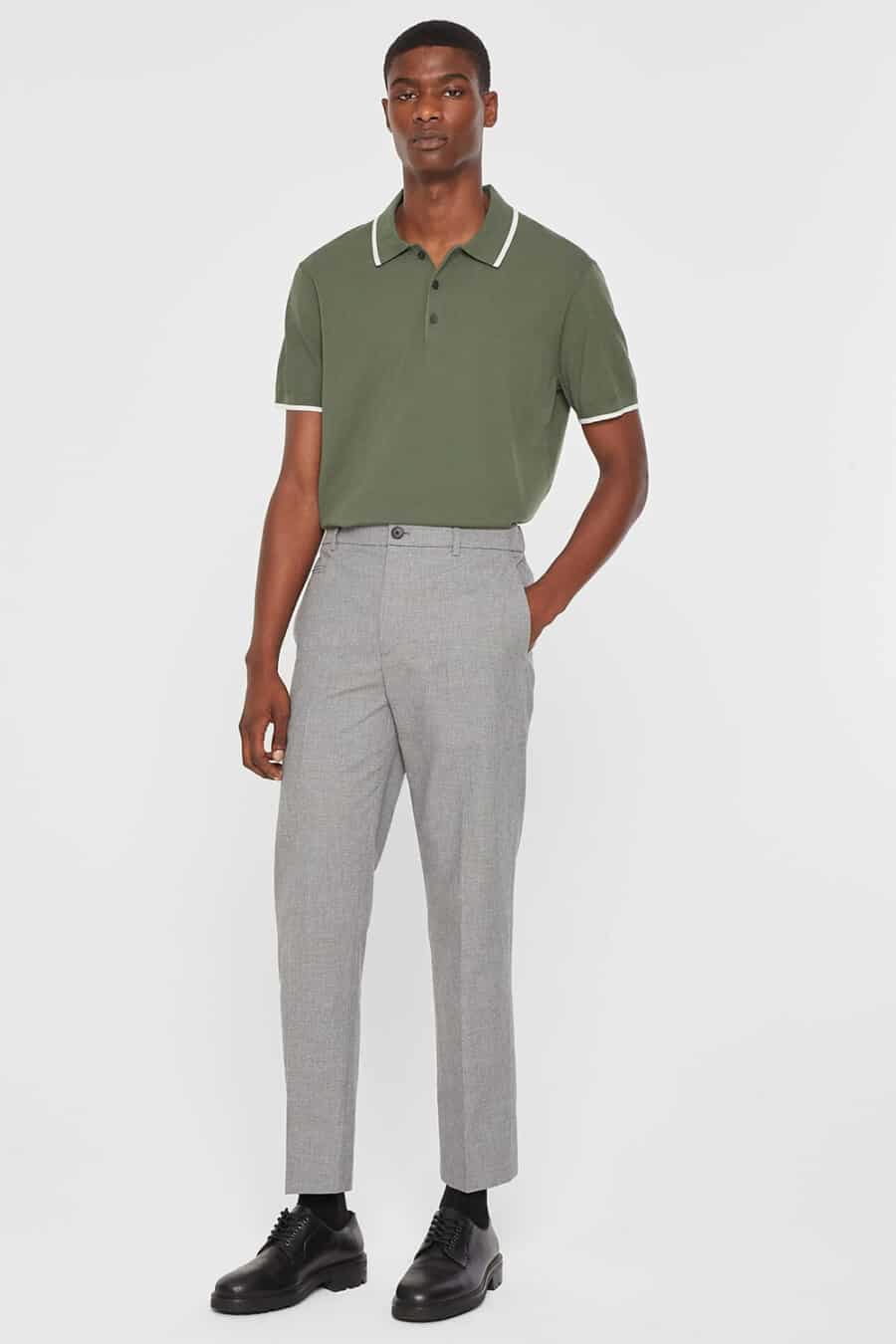 Men's cropped grey trousers, green polo shirt tucked in and black Derby shoes outfit