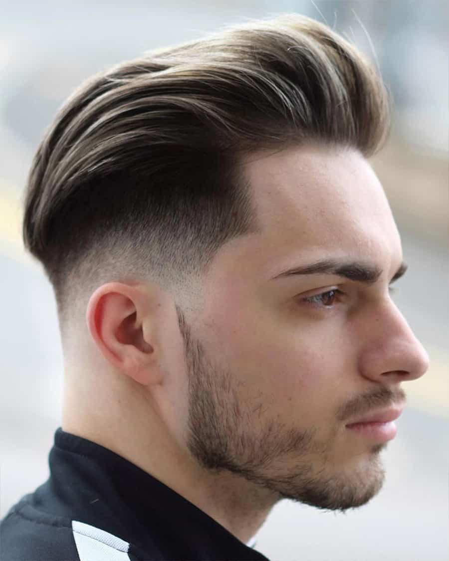 Man with a long, swept back pompadour and high taper fade