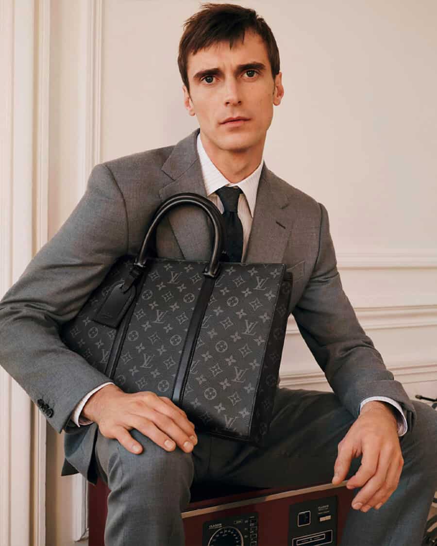 Man in grey suit holding a luxury tote bag