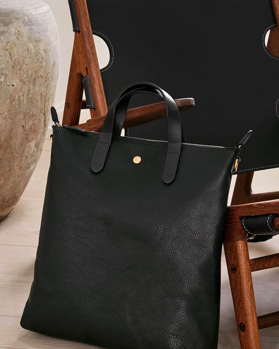 Luxury black leather tote balanced against chair