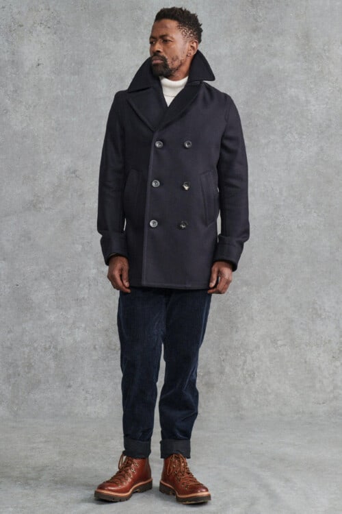 Men's navy corduroy trousers, white roll neck jumper, navy peacoat and brown leather hiking boots outfit