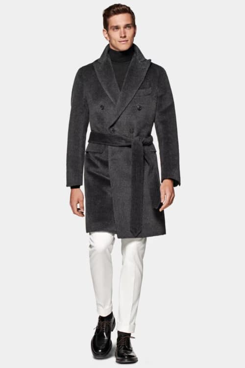 Men's white trousers, charcoal turtleneck, dark grey double breasted belted polo overcoat and leather Derby shoes outfit