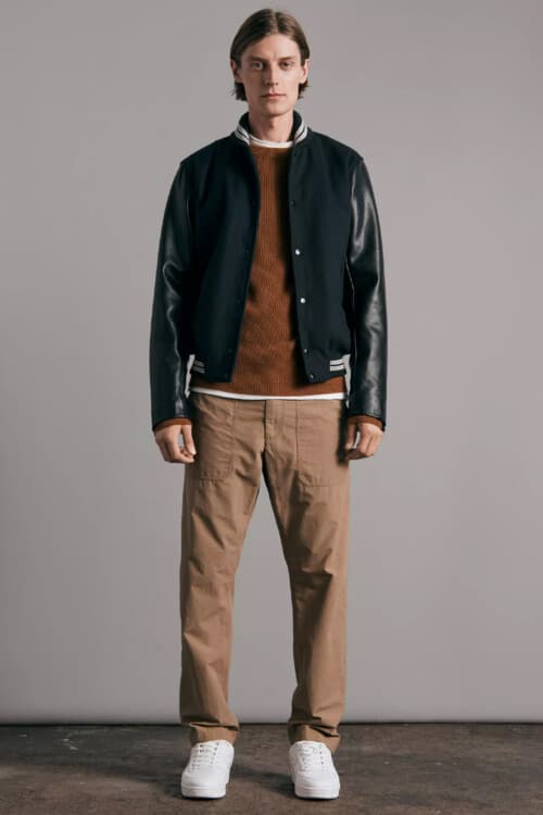 Men's khaki pants, brown ribbed jumper, black varsity jacket and white sneakers outfit