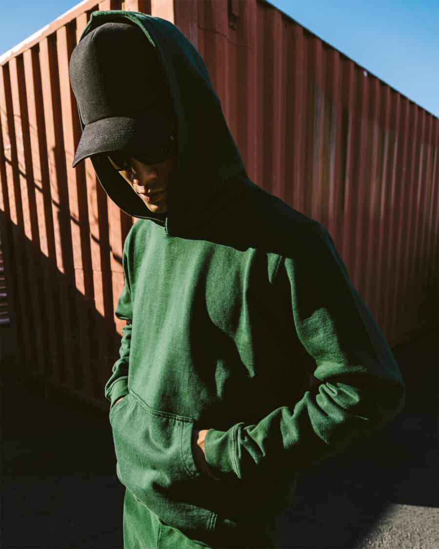 Man wearing a green heavyweight hoodie and black baseball cap