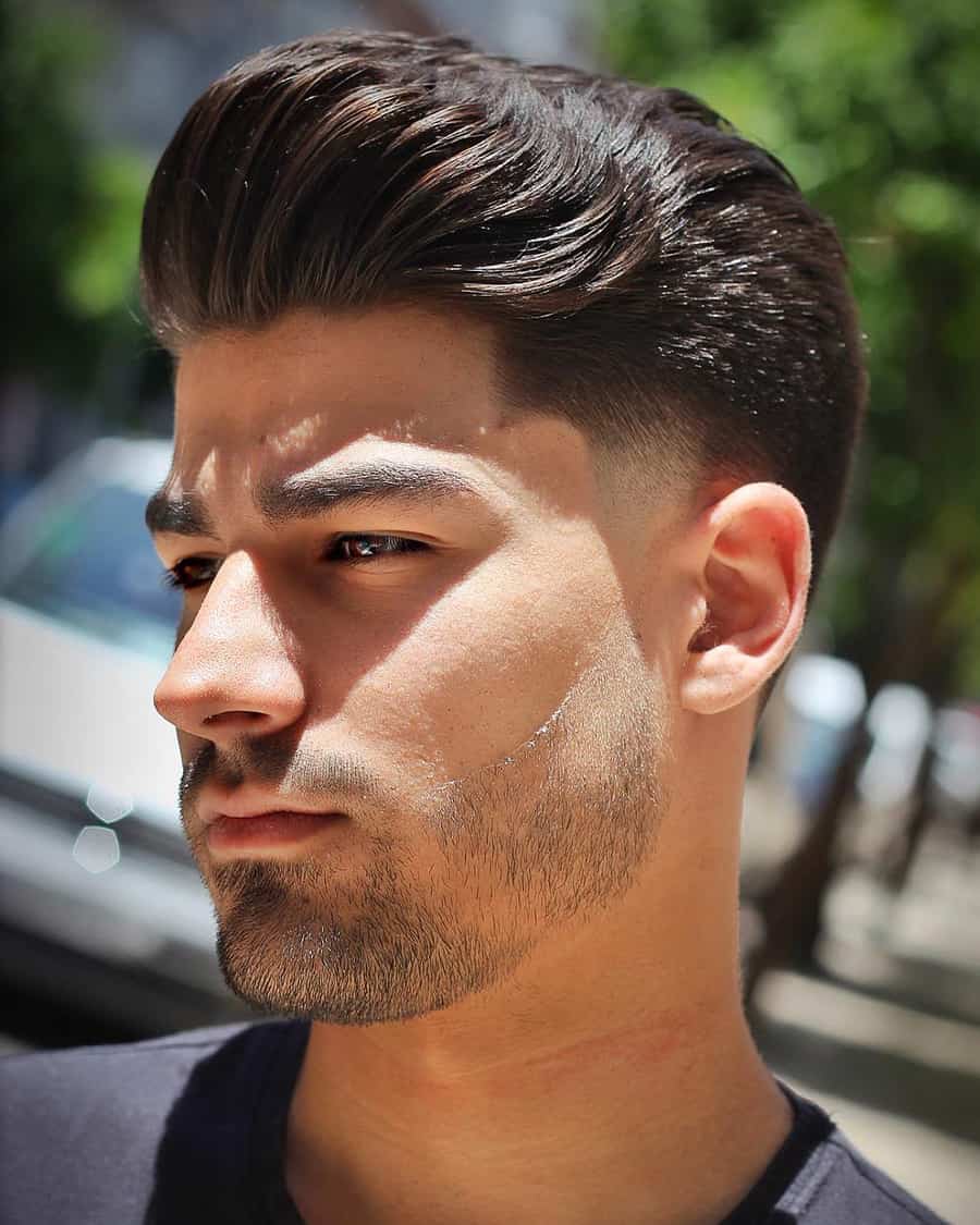 Men's swept back pompadour hairstyle with temple fade