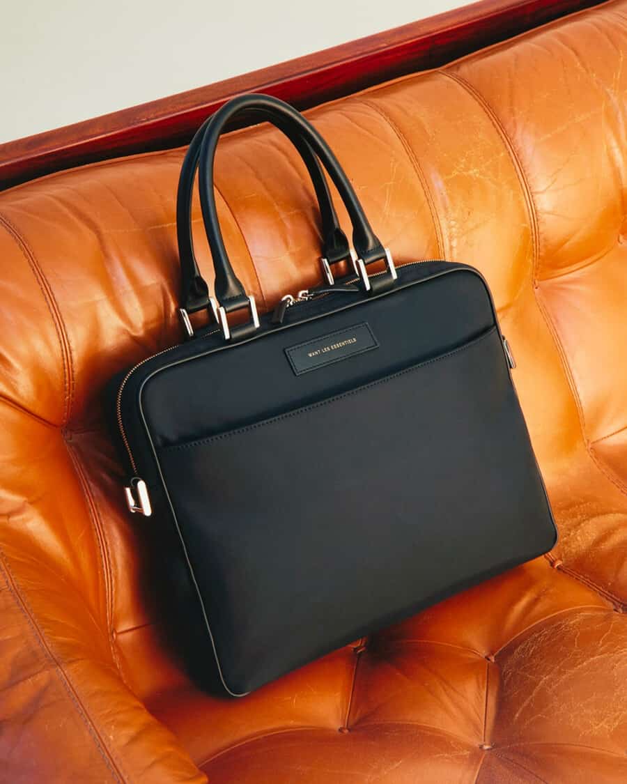 Luxury black attache case sat on tan leather sofa