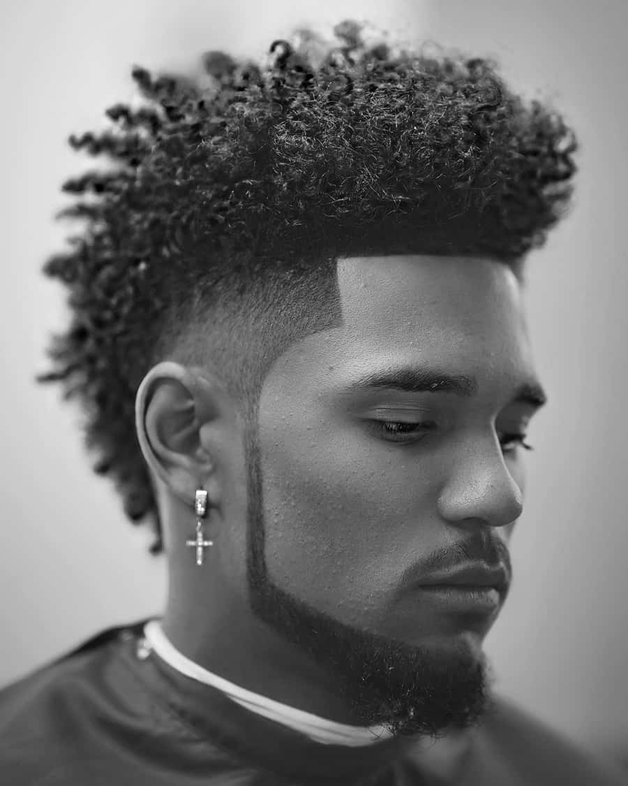 Black man with long curls in mohawk shape with drop fade