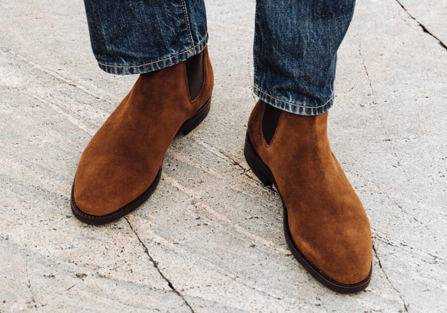 Man wearing tan suede Chelsea boots with blue jeans